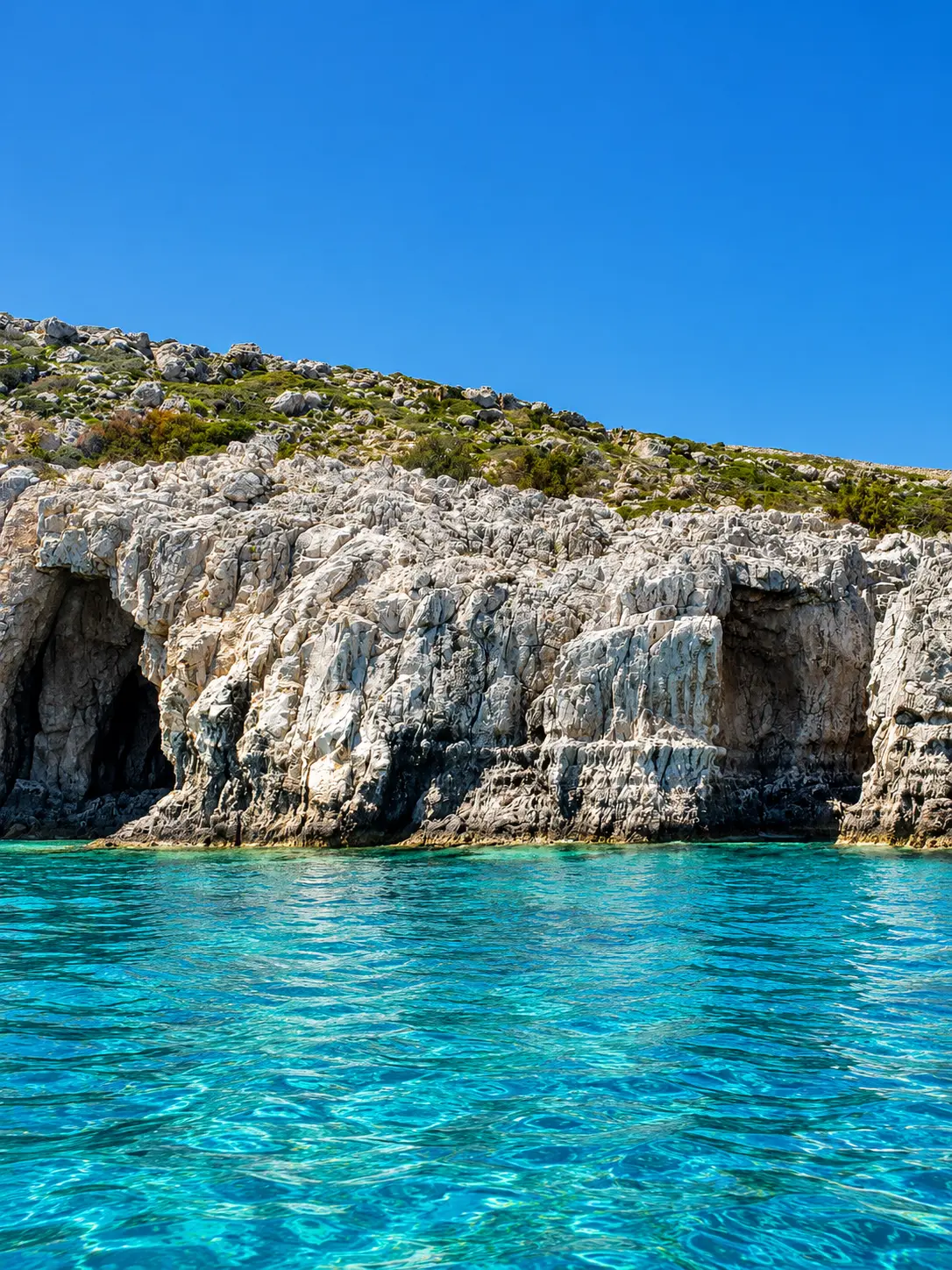 Rocky sea caves and bright water along the Rhodes coastline