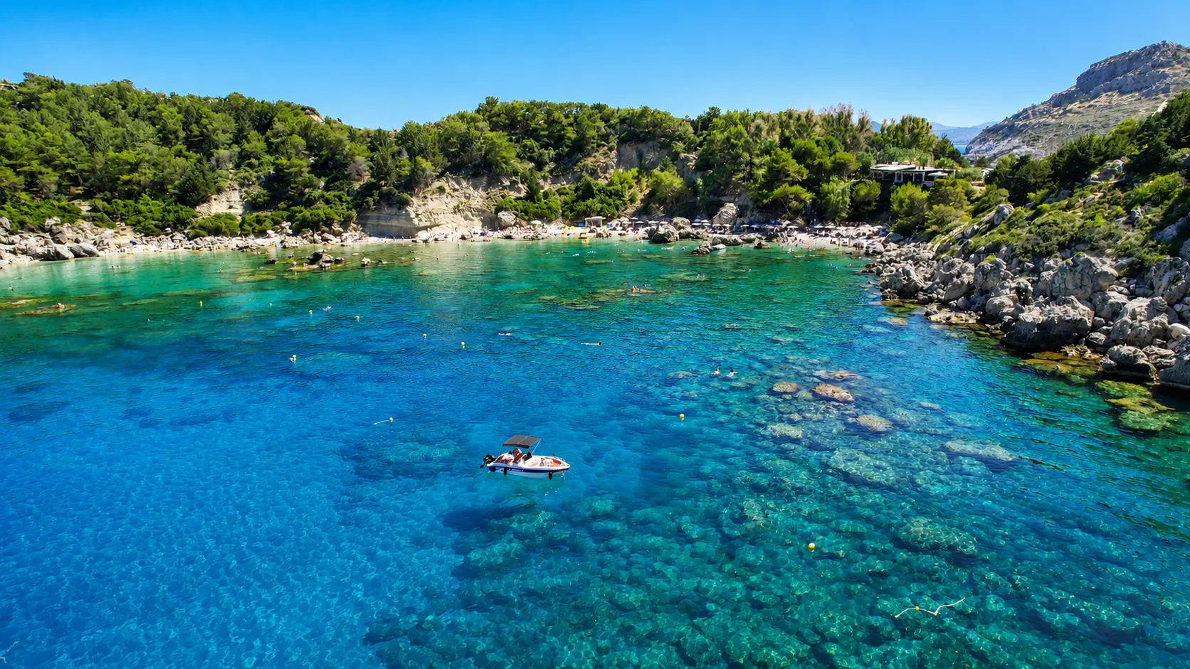 Boat floating in the clear water of Anthony Quinn Bay